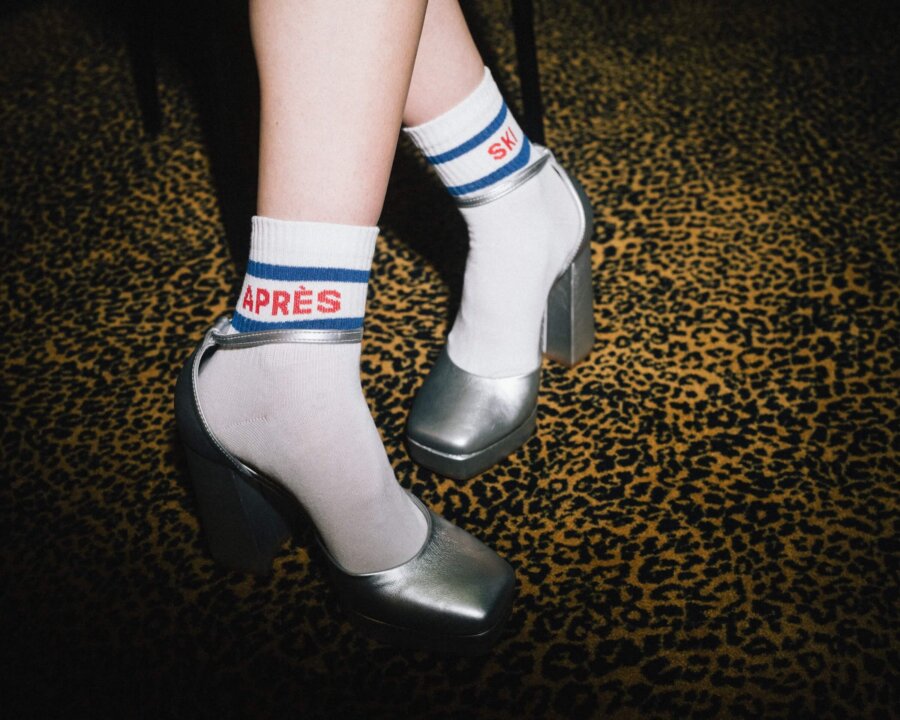 Elegante High Heels mit modischen Socken im Après-Ski-Stil auf einem auffälligen Leopardenmusterboden.