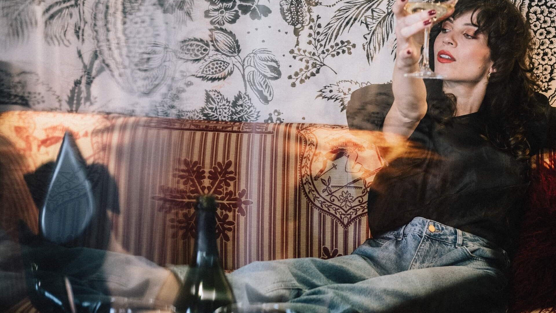 Eine Frau genießt einen Cocktail in der stilvollen Lounge des Hotel Edelweiss in Lech/Zürs, umgeben von elegantem Design.