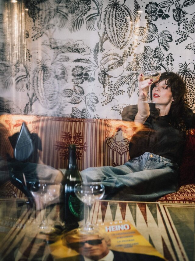 Eine Frau genießt einen Cocktail in der stilvollen Lounge des Hotel Edelweiss in Lech/Zürs, umgeben von elegantem Design.