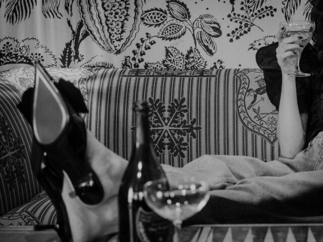 Elegante Füße in schwarzen Schuhen auf einem Sofa, während ein Drink serviert wird. Stilvolles Ambiente im Hotel Edelweiss.