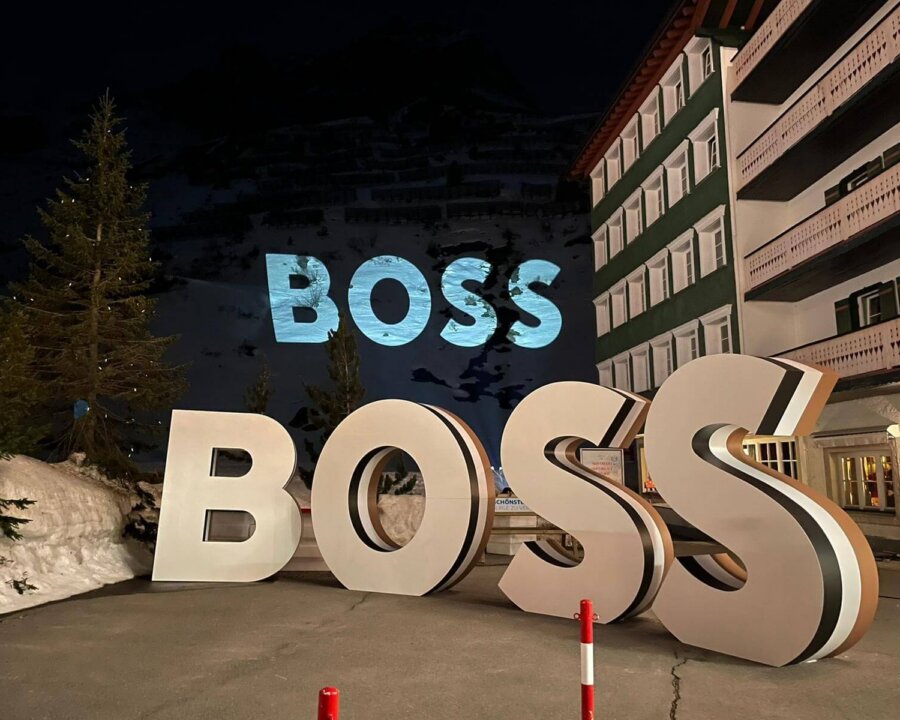 Beleuchtete BOSS-Buchstaben vor dem Hotel Edelweiss in Lech/Zürs, umgeben von winterlicher Landschaft.