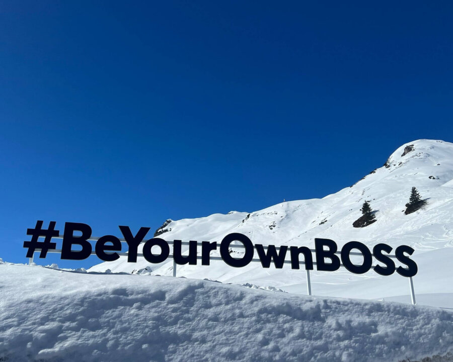 Schneelandschaft in Lech/Zürs mit dem #BeYourOwnBOSS Schriftzug vor blauem Himmel, ideal für alpine Abenteuer.