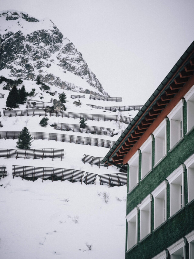 Hotel Edelweiss in Lech mit schneebedecktem Berg und typischen Zaunstrukturen im Winter.
