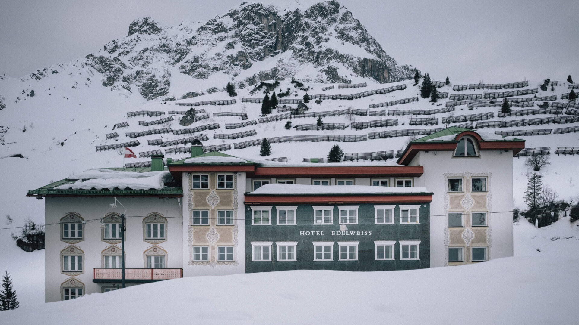 Hotel Edelweiss in Lech/Zürs, umgeben von verschneiten Bergen und winterlicher Landschaft. Idealer Ort für Wintersport.