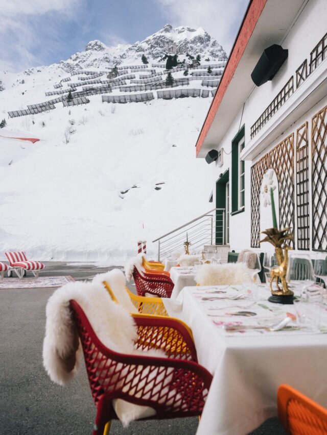 Gemütlicher Außenbereich des Hotels Edelweiss in Lech/Zürs, umgeben von schneebedeckten Bergen und stilvollen Möbeln.