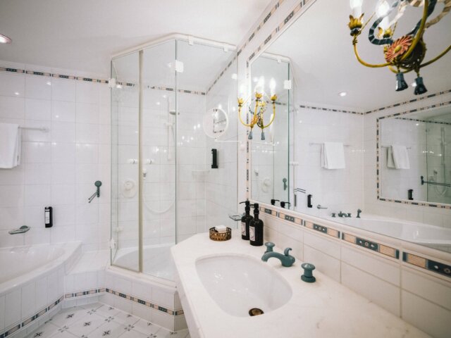 Elegantes Badezimmer im Hotel Edelweiss mit moderner Dusche, Badewanne und stilvollen Armaturen in Lech/Zürs.
