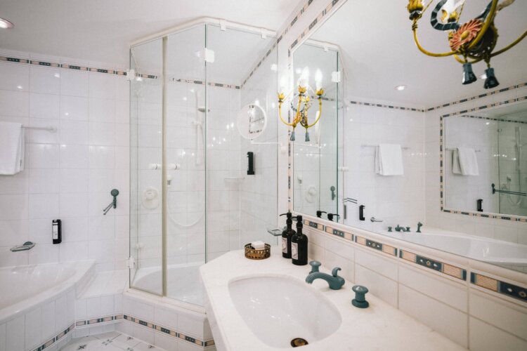 Elegantes Badezimmer im Hotel Edelweiss mit moderner Dusche, Badewanne und stilvollen Armaturen in Lech/Zürs.