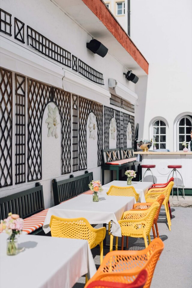 Bunte Außenterrasse des Hotels Edelweiss in Lech/Zürs mit Tischen, Stühlen und frischen Blumenbouquets.