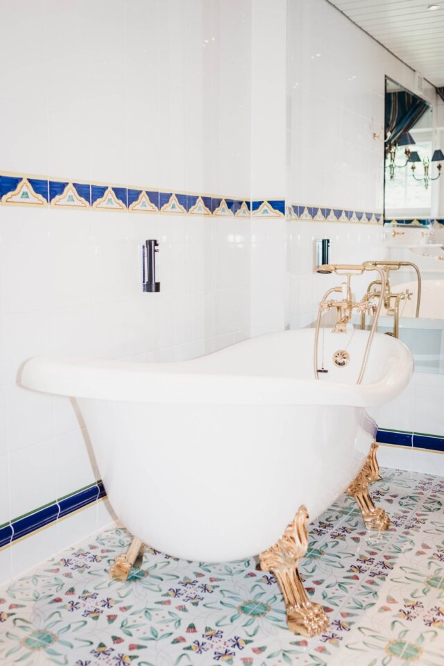Elegante freistehende Badewanne mit goldenen Füßen im stilvollen Badezimmer des Hotels Edelweiss in Lech/Zürs.