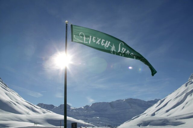 Flagge des Hotel Edelweiss weht im Schnee, vor einer beeindruckenden Berglandschaft in Lech/Zürs am Arlberg.