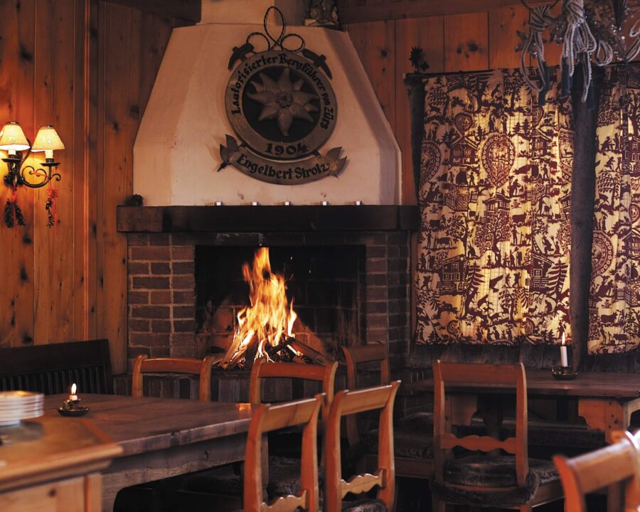 Gemütlicher Restaurantbereich im Hotel Edelweiss mit Kamin und traditioneller Holzdecke in Lech/Zürs am Arlberg.