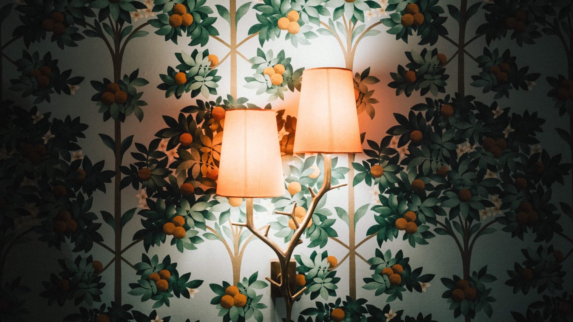 Wandlampe vor einem floral gemusterten Hintergrund im Hotel Edelweiss, Lech/Zürs am Arlberg. Gemütliche Atmosphäre.