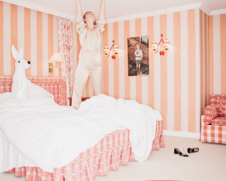 Frau in luxuriösem Hotelzimmer des Hotel Edelweiss in Lech, voller Farben und kreativer Details. Entspannung und Spaß vereint.