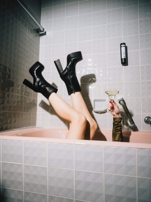 Füße in hohen Schuhen zeigen Genussmoment in Badewanne mit Cocktail, stilvoller Bezug zu Hotel Edelweiss in Lech.