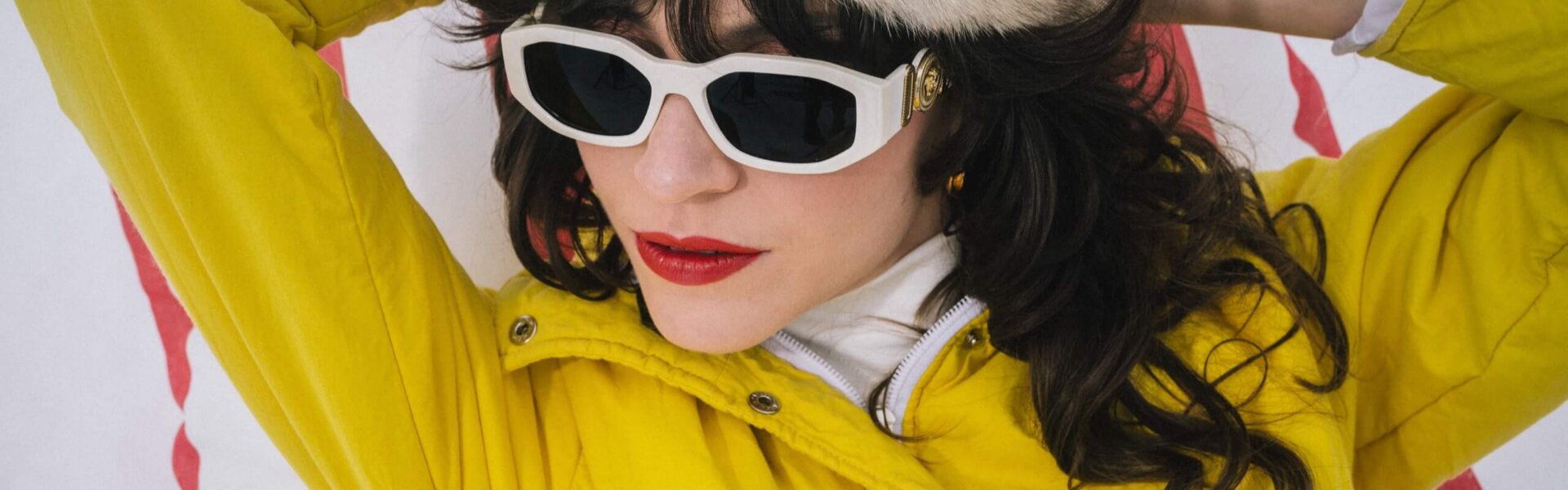 Frau in gelber Jacke und weißen Sonnenbrillen mit Pelzmütze, entspannt im Schnee im Hotel Edelweiss, Lech/Zürs.