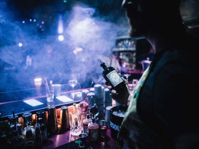 Barkeeper in stilvollem Ambiente mit Glas und Cocktails, ideal für einen Abend im Hotel Edelweiss in Lech/Zürs.