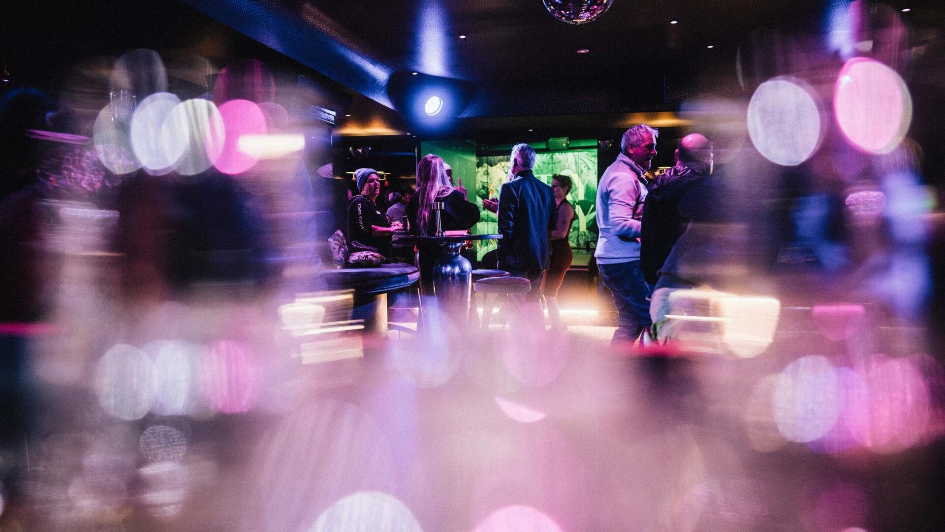 Bunt erleuchtete Bar im Hotel Edelweiss mit geselligen Gästen und lebhafter Atmosphäre in Lech/Zürs.