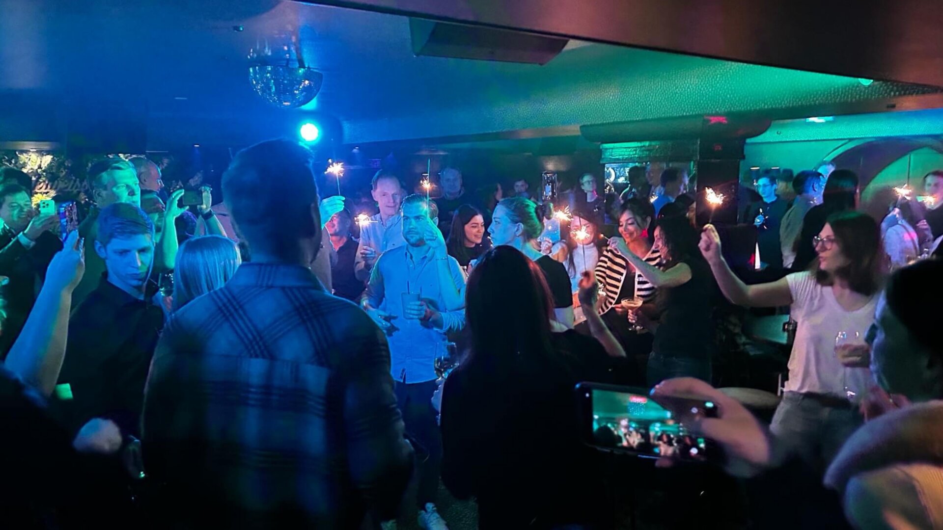 Feierliche Stimmung im Hotel Edelweiss: Gäste tanzen und genießen die Musik bei funkelnden Lichtern und Drinks.