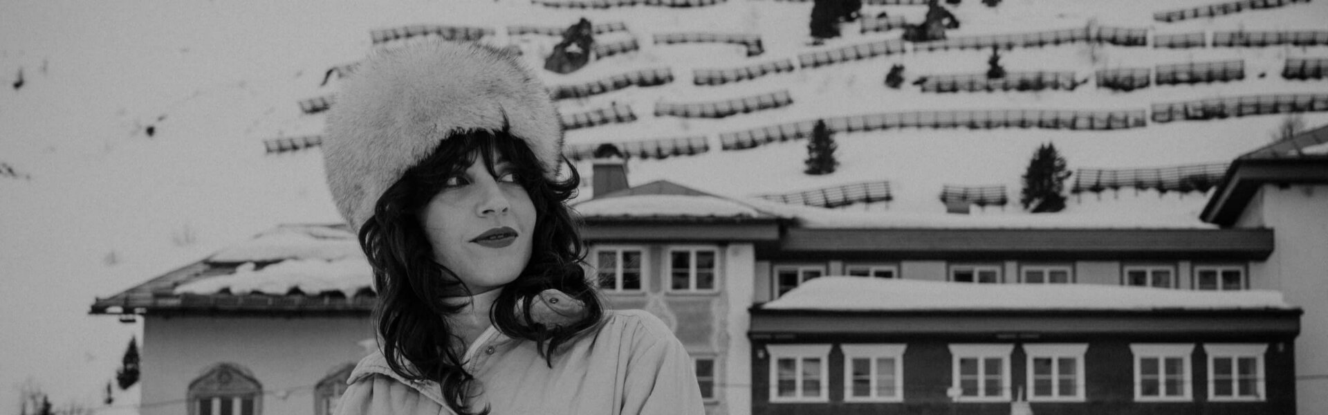 Frau mit Pelzmütze vor dem Hotel Edelweiss in der verschneiten Winterlandschaft von Lech/Zürs am Arlberg.