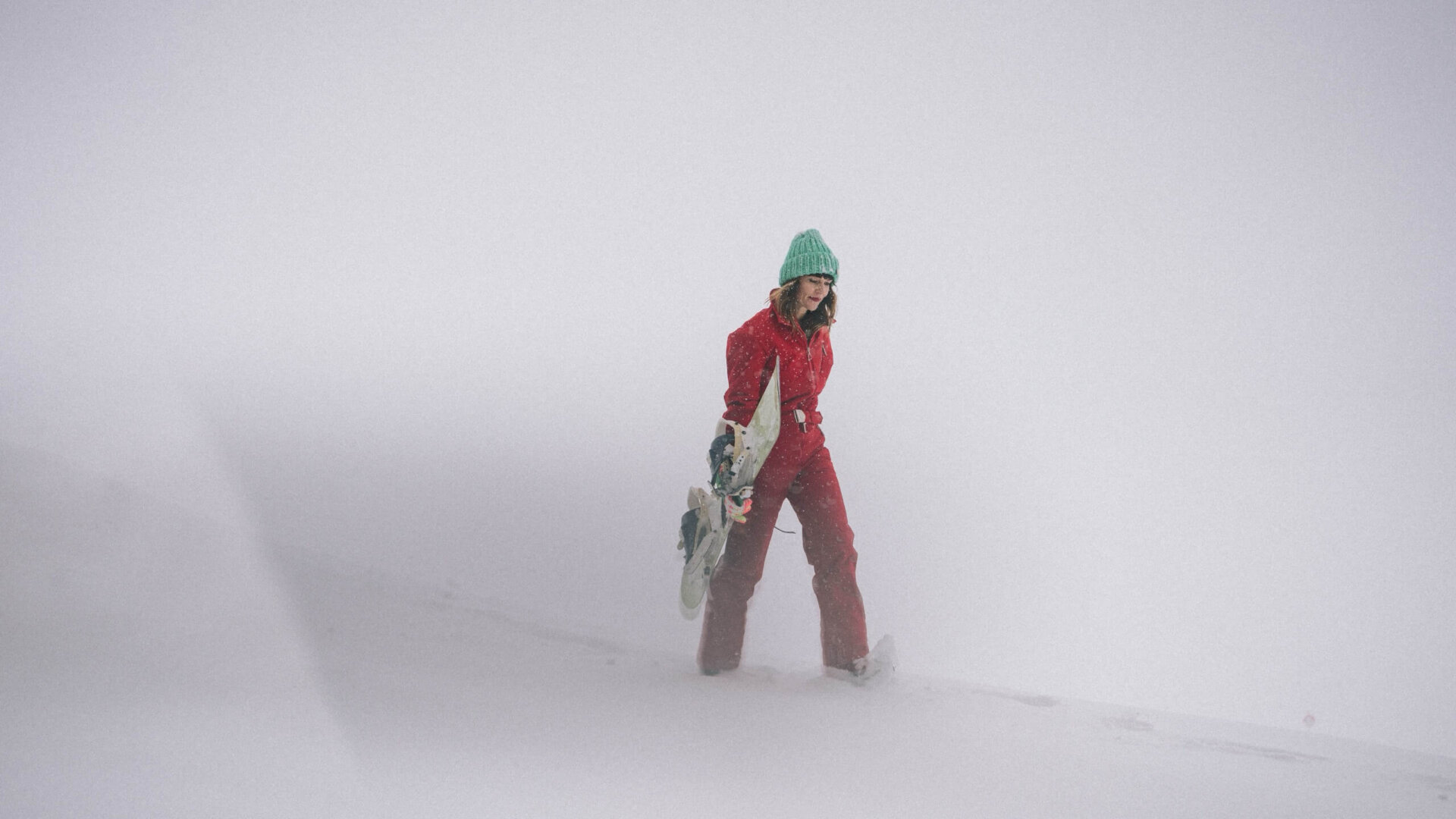 Eine Frau in roter Skibekleidung wandert durch verschneite Landschaft im Nebel, ideal für Winterabenteuer in Lech/Zürs.
