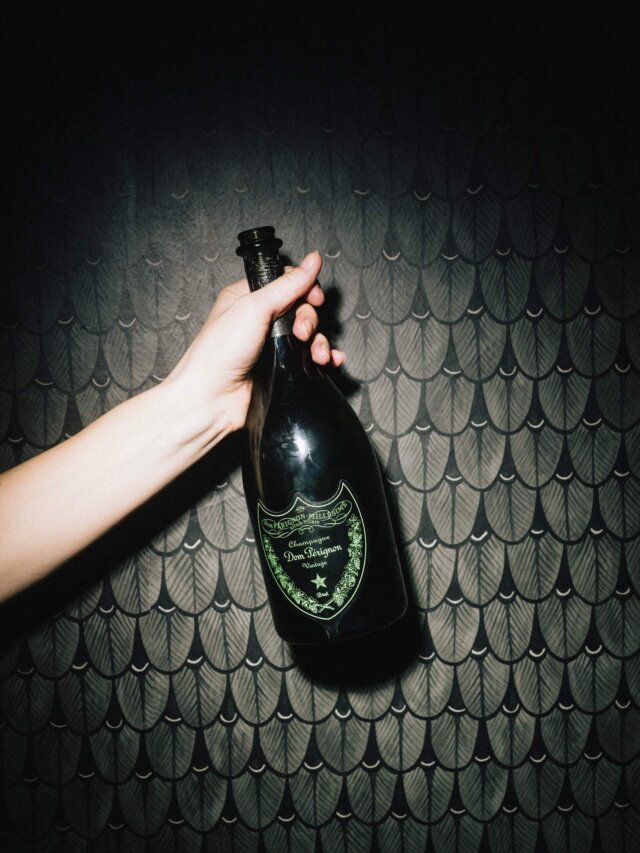 Hand hält eine Flasche Dom Pérignon Champagner vor einer elegant gestalteten Wand im Hotel Edelweiss in Lech/Zürs.