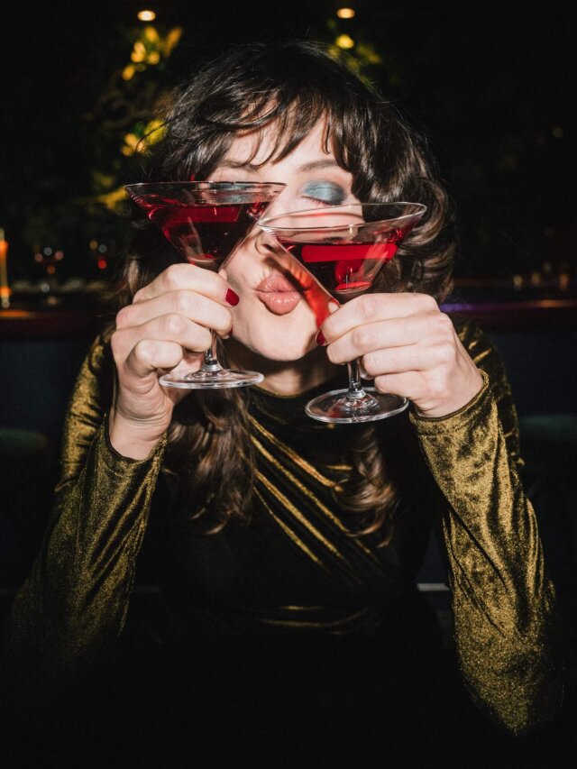 Frau mit rotem Cocktail in beiden Händen, genießt den Abend in der stilvollen Bar des Hotels Edelweiss in Lech.
