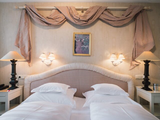 Gemütliches Zimmer im Hotel Edelweiss mit eleganter Einrichtung, nostalgischem Bettkopfteil und stilvoller Beleuchtung.