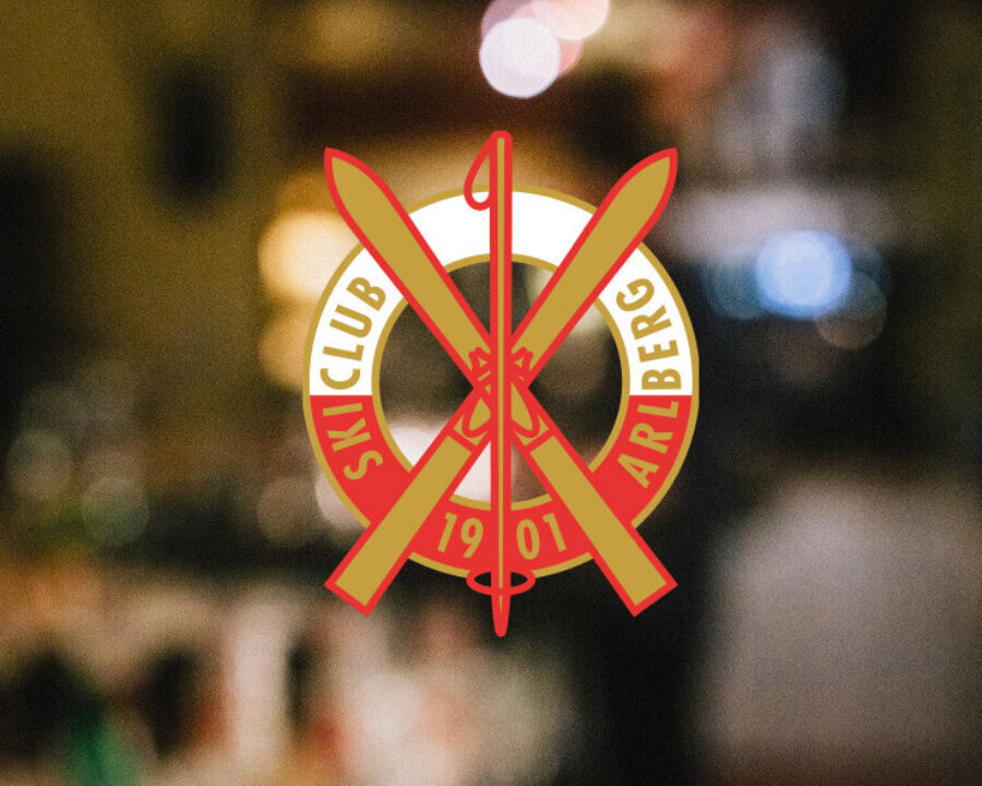 Logo des Ski Clubs Arlberg mit gekreuzten Skiern, das die Verbindung zum Skiurlaub in Lech/Zürs am Arlberg symbolisiert.