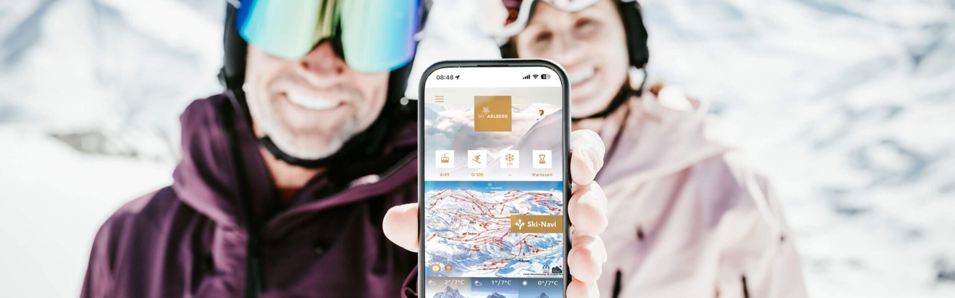 Skifahrer zeigen stolz die Ski-App vor atemberaubender Berglandschaft in Lech/Zürs am Arlberg.