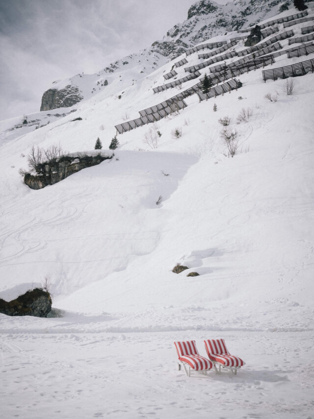 Zwei rot-gestreifte Liegestühle im schneebedeckten Gelände von Lech/Zürs am Arlberg, ideal zum Entspannen.