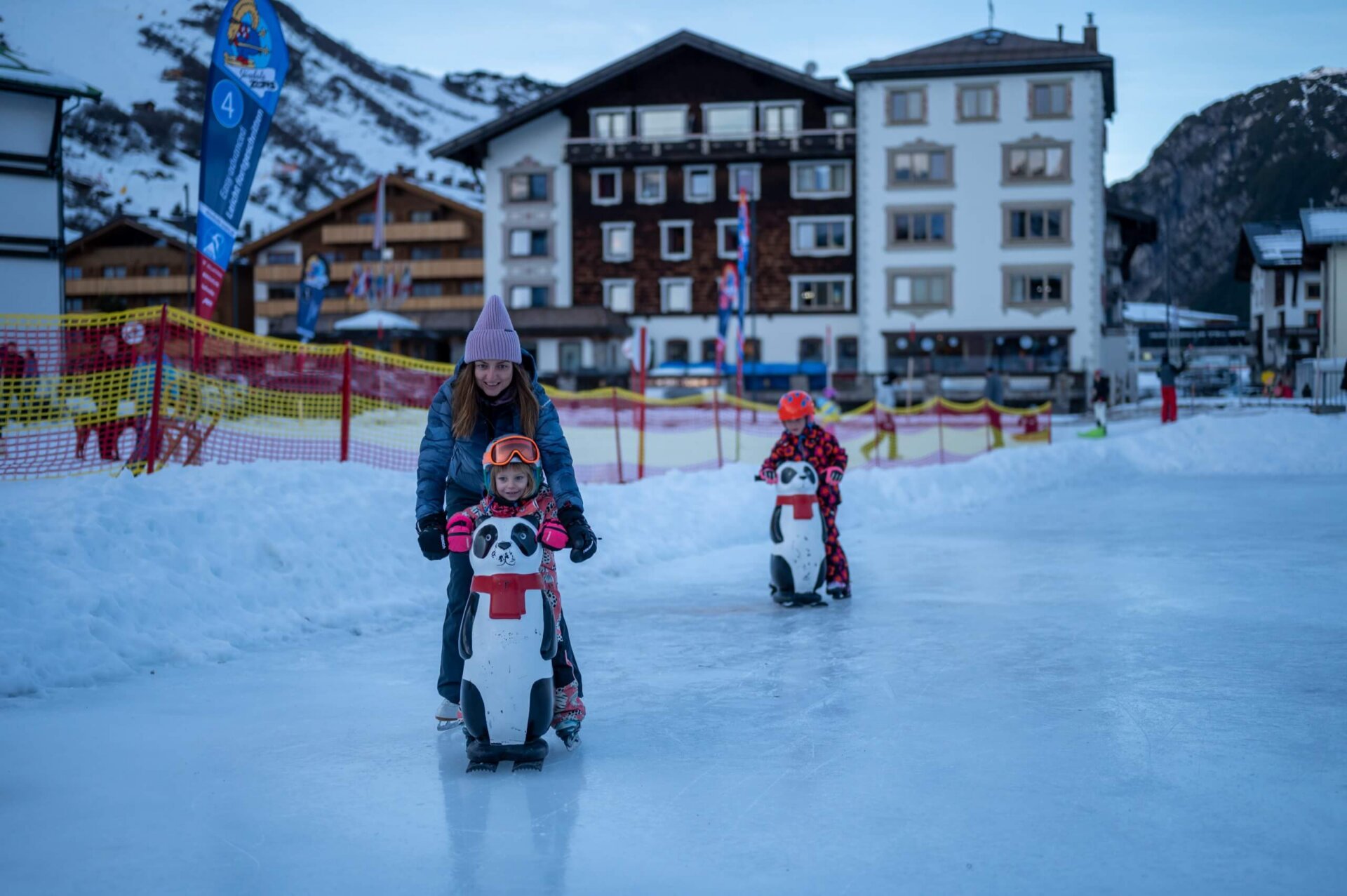 Familie genießt das Eislaufen am Hotel Edelweiss in Lech/Zürs auf einem kinderfreundlichen Eisplatz.