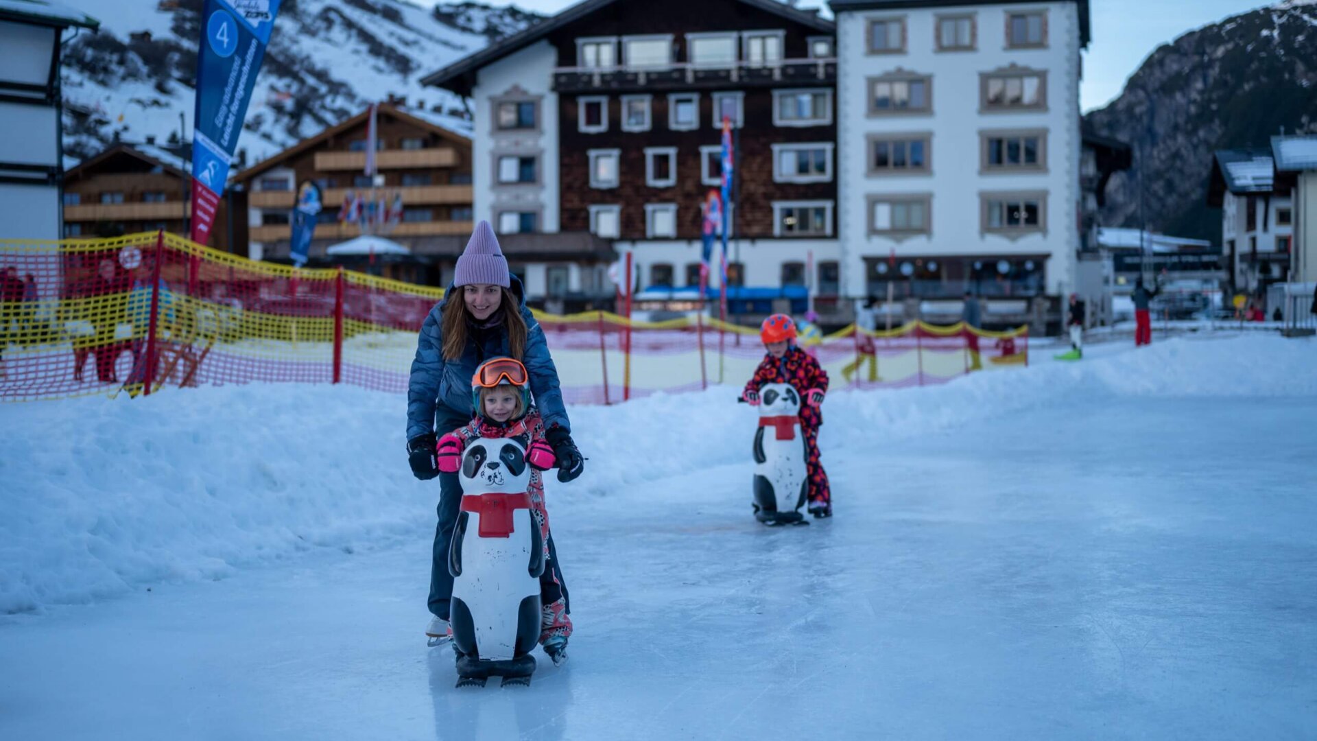 Familie genießt das Eislaufen am Hotel Edelweiss in Lech/Zürs auf einem kinderfreundlichen Eisplatz.