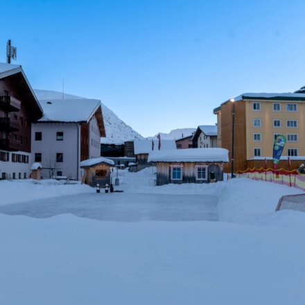 Winterliche Aussicht auf das Hotel Edelweiss in Lech/Zürs, umgeben von Schnee und einer Eisfläche.