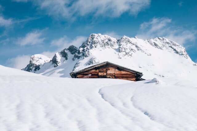 Schneebedeckte Berge und eine liebevoll errichtete Alm in der malerischen Winterlandschaft von Lech/Zürs am Arlberg.