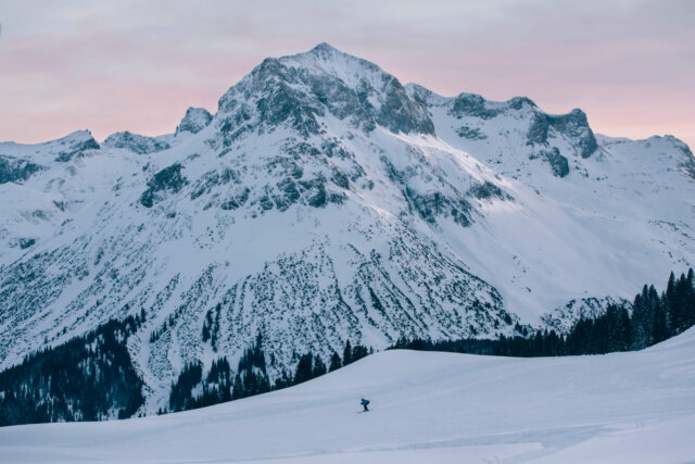 Skifahrer auf unberührtem Schnee vor majestätischen Bergen in Lech/Zürs am Arlberg.
