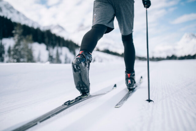 Skifahrer beim Langlaufen auf verschneiten Pisten in Lech/Zürs am Arlberg, umgeben von malerischer Berglandschaft.