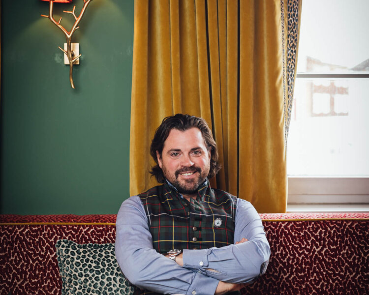 Mann in traditioneller Tracht sitzt entspannt auf einem Sofa im Hotel Edelweiss, Lech/Zürs am Arlberg.