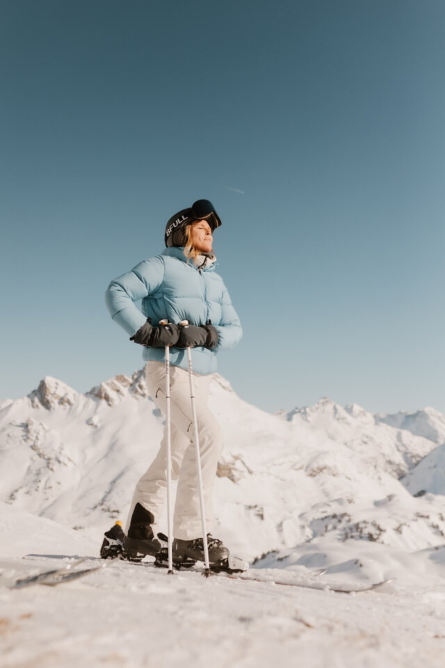 Eine Skifahrerin genießt die Aussicht auf die schneebedeckten Berge in Lech/Zürs am Arlberg. Perfekte Winterbedingungen!