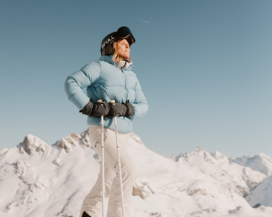 Eine Skifahrerin genießt die Aussicht auf die schneebedeckten Berge in Lech/Zürs am Arlberg. Perfekte Winterbedingungen!