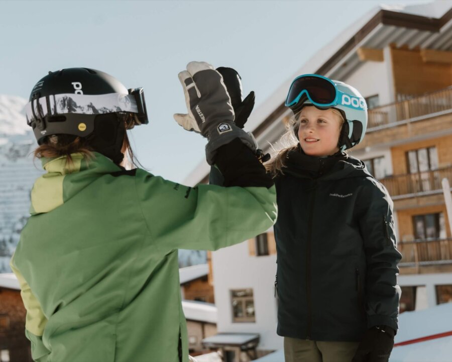 Zwei Skifahrer begrüßen sich in der traumhaften Berglandschaft von Lech/Zürs am Arlberg vor dem Hotel Edelweiss.