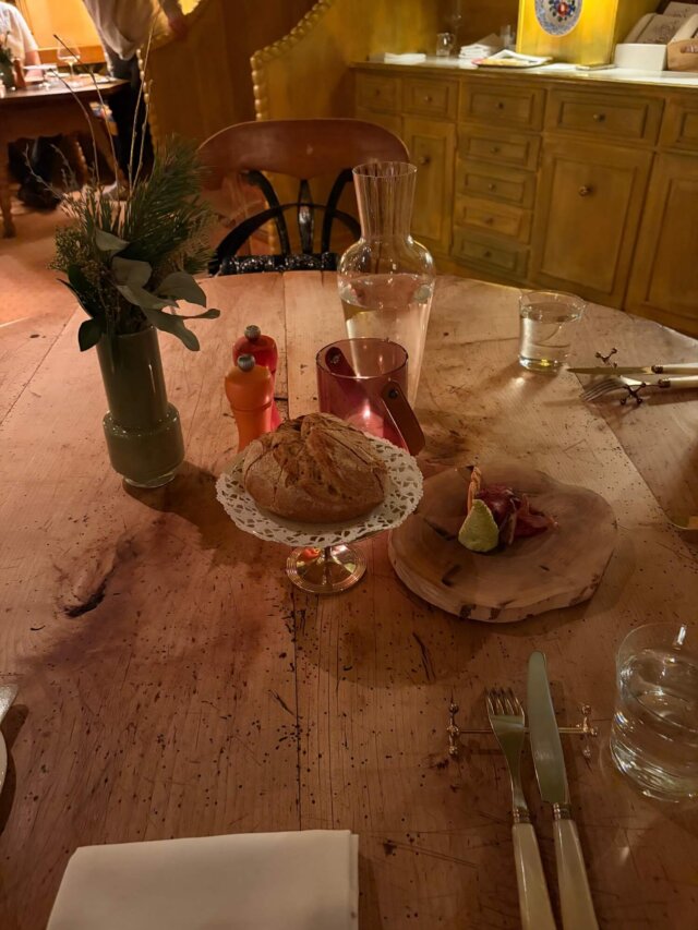 Gemütlicher Tisch im Hotel Edelweiss mit frischem Brot, Wasser und dekorativem Geschirr in Lech/Zürs.