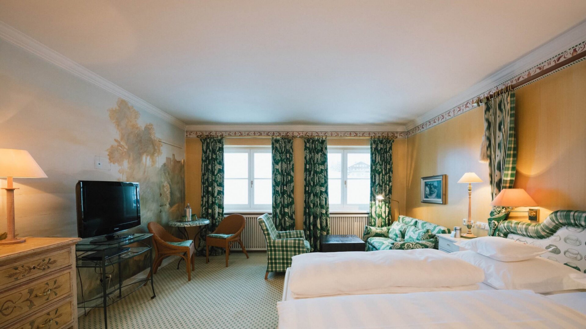 Gemütliches Zimmer im Hotel Edelweiss mit elegantem Design, Fernseher, Sitzbereich und Blick auf die Berge in Lech/Zürs.