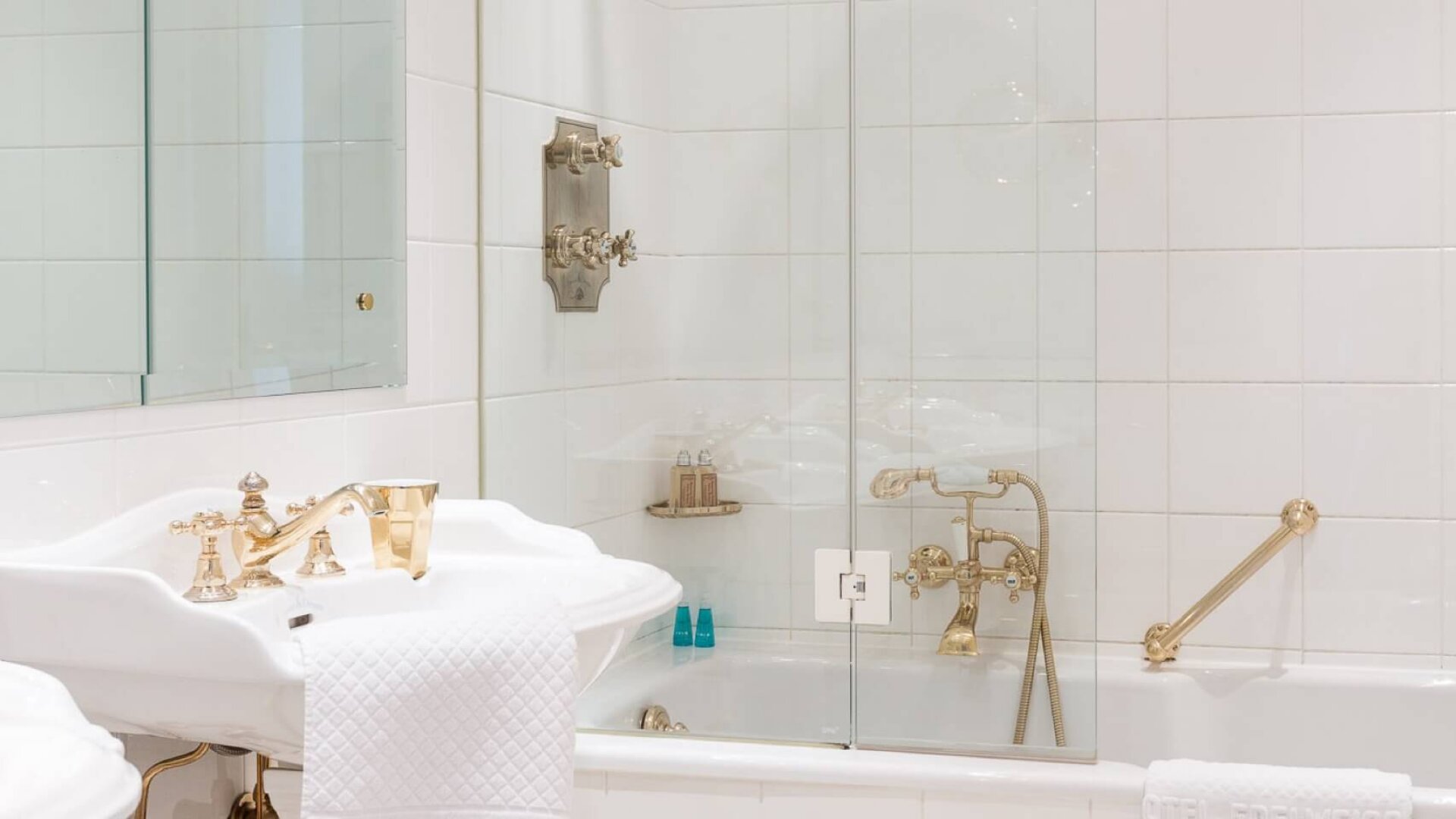 Elegantes Badezimmer im Hotel Edelweiss in Lech/Zürs mit Luxusarmaturen und stilvollem Fliesenboden.