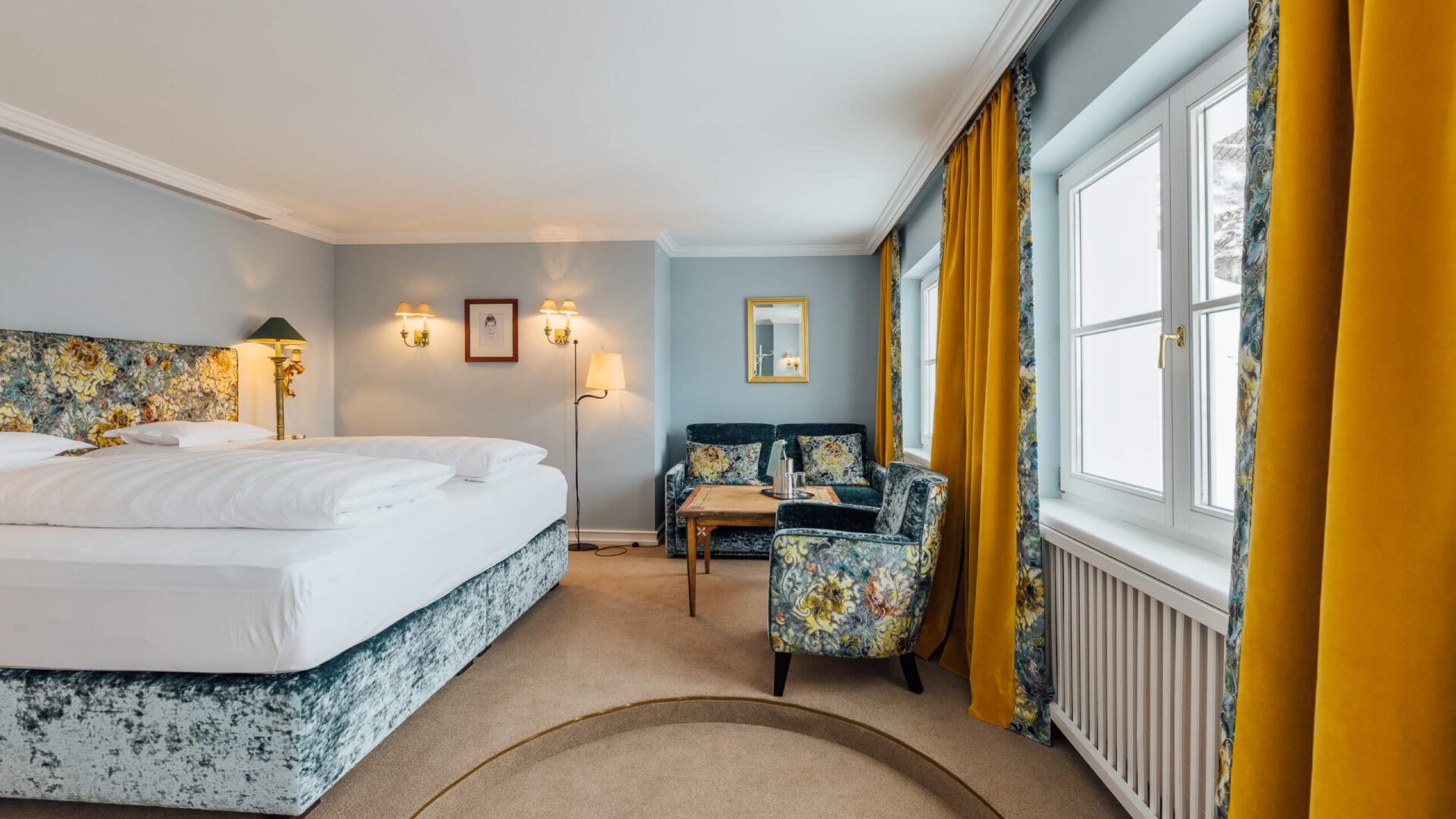 Gemütliches Hotelzimmer im Hotel Edelweiss mit floralem Design, großem Bett und einladendem Sitzbereich in Lech/Zürs.