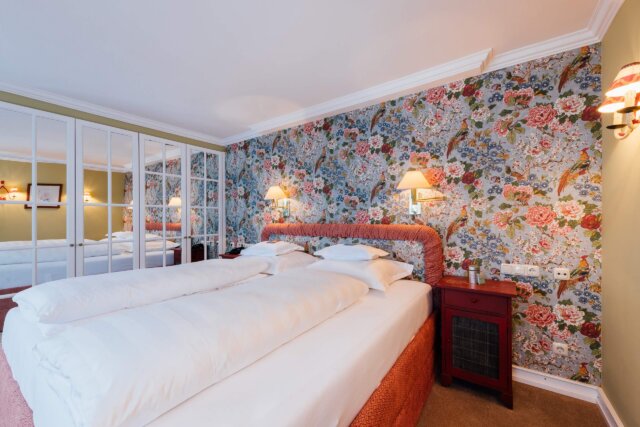 Gemütliches Doppelzimmer im Hotel Edelweiss mit floraler Tapete, gemütlichen Betten und stilvollem Interieur.