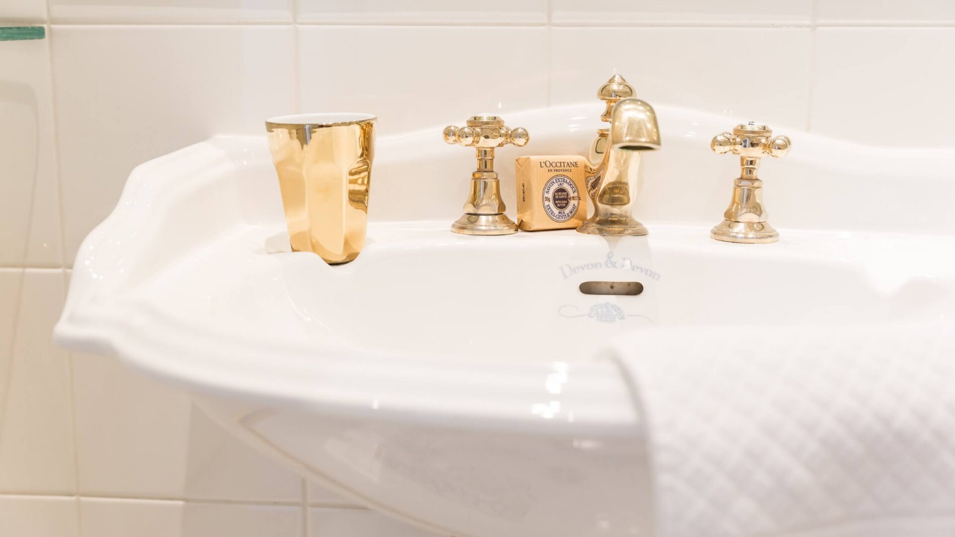 Elegantes Waschbecken im Hotel Edelweiss mit goldenen Armaturen und stilvollem Zubehör in Lech/Zürs am Arlberg.