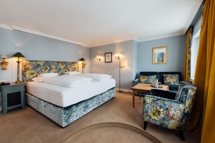 Geräumiges Hotelzimmer im Hotel Edelweiss in Lech/Zürs mit elegantem Interieur und gemütlicher Sitzecke.