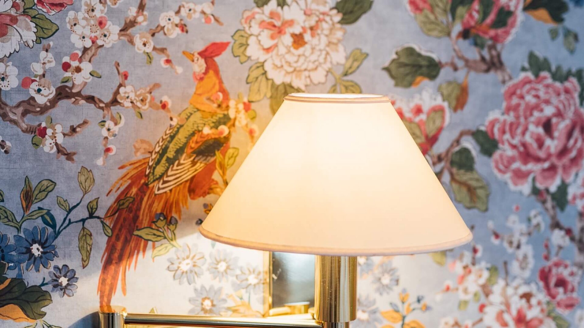 Wandleuchte vor floralem Wanddesign im eleganten Ambiente des Hotel Edelweiss in Lech/Zürs am Arlberg.