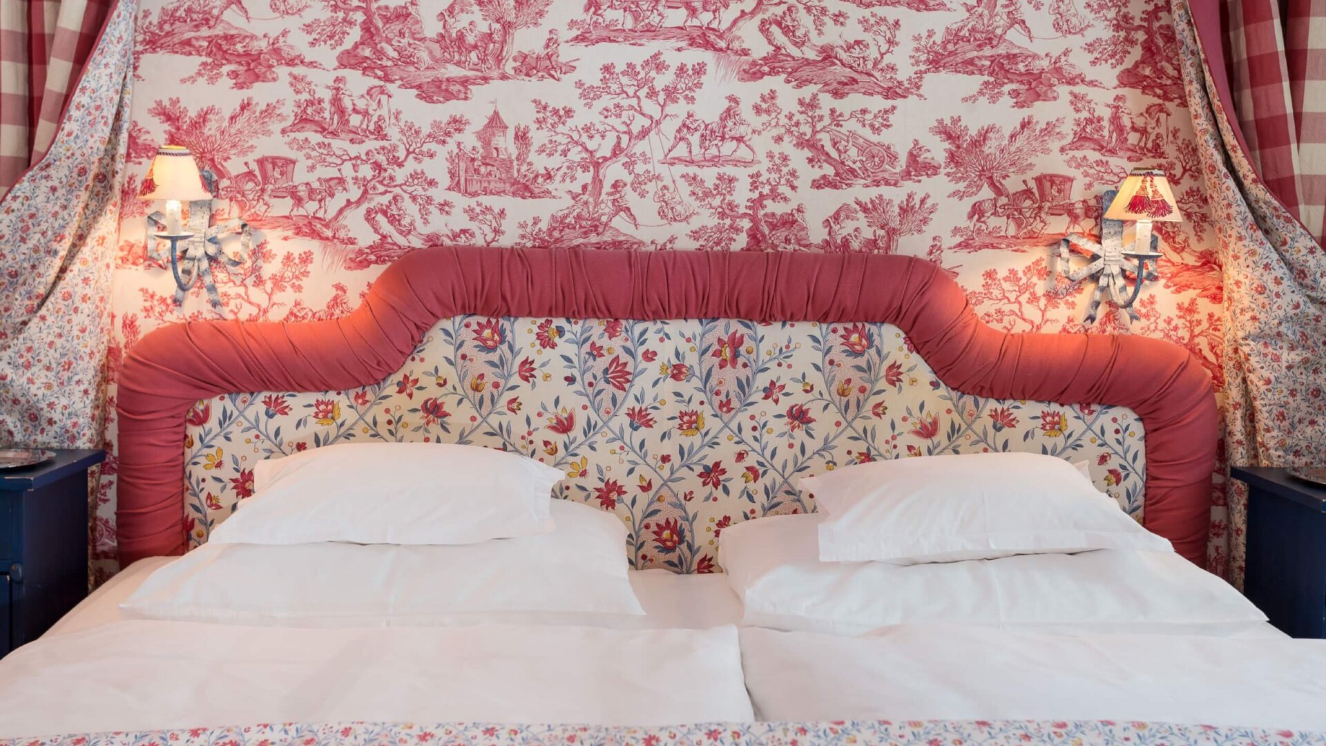 Elegantes Doppelbett im Hotel Edelweiss, umgeben von floralen Mustern und sanfter Beleuchtung in einem romantischen Ambiente.