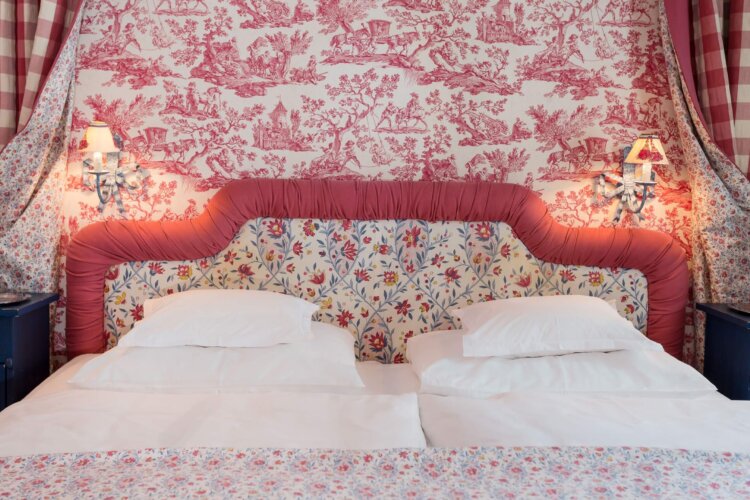 Elegantes Doppelbett im Hotel Edelweiss, umgeben von floralen Mustern und sanfter Beleuchtung in einem romantischen Ambiente.